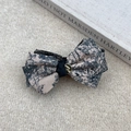 Close-up of Toile de Jouy print bow hair claw with elegant golden metal relief button - Khaki