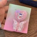 Detail von süßem rosa Herz-Clip und floraler Schmetterlings-Haarklammer auf Karte - Schleifen Herz