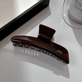 Detailed close-up of dark brown acetate claw clip with white French lettering - Geometric