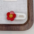 Detail view of a handmade acetate flower hair clip with a red floral design and gold text - Red Floral Hair Pin