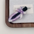 Pince à cheveux tissée violette et blanche avec nœud sur un plateau en bois - Violet