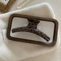 Detail view of large leopard print hair claw clip on white fleece with pearls - Dark Leopard Hanger Style