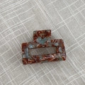 Detail view of handmade marble acetate hair claw clip on neutral fabric background - Mint Green Brown Gradient