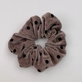 Détail d'un chouchou en velours marron à pois noirs avec une texture douce et souple - Café