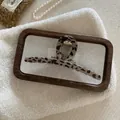Close-up of leopard print hair claw clip on tray with elegant pearl necklace detail - Light Leopard Bar Style