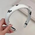 Détail d'un serre-tête crème avec broderies de papillons noirs et texture en maille côtelée - Serre-tête Blanc Cassé