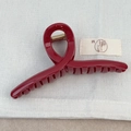 Dettaglio macro di un fermaglio per capelli rosso scuro lucido con molla dorata - Incrociato