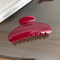 Detail of burgundy large hair claw clip with glossy finish and curved teeth on a mirror base - Semicircle Style