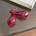 Detailed view of a burgundy glossy resin hair claw clip on a stylish wooden desk surface - Chevron Style