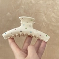 Detail of cream acetate hair claw clip with colorful rhinestones on a warm background - Hanger Style