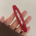 Dettaglio ravvicinato di un fermaglio ovale in acetato rosso con base in metallo - Rosso