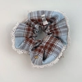 Detail view of blue plaid scrunchie with white lace edges and a golden love charm - Lace Edge Scrunchie