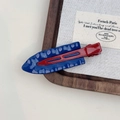 Detail of red and blue wave pattern metal hair clip with glossy finish on textured fabric - Blue