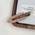 Detail of elegant wavy hair clip with cream marble texture and retro dark brown base - Khaki