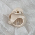 Close-up of a minimalist cream resin hair claw clip with golden metal spring on paper - Beige Geometric Style