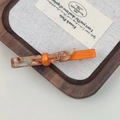 Close-up of orange and marble resin hair clip on a minimalist wooden tray display - Orange