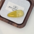 Détail d'une barrette goutte en acétate jaune sur un plateau en bois avec texture canevas - Vert Moutarde