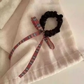 Dettaglio di un elastico per capelli con fiocco scozzese e lunghi nastri su lino beige - Stile Quadri Britannici Con Velluto Nero