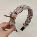 Dettaglio di un cerchietto in tessuto a righe con fiocco marrone e ciondolo a cuore oro - Cerchietto Pieghettato Tè al Latte