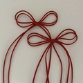 Detail view of a pair of red suede bow hair clips with silver metal spring fasteners - Burgundy
