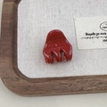 Close-up of a red acetate claw clip with Barrette la France engraving on a rustic tray - Burgundy