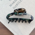 Detail of French acetate hair claw clip with dark green marble texture and amber inlay - Green