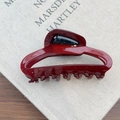 Close-up of burgundy French hair claw with black accents on a grey book background - Burgundy