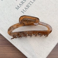 Macro detail of tortoiseshell acetate hair claw clip with cutout design on linen background - Brown