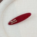 Vue macro d'une barrette rouge brillant ornée de l'inscription dorée Barrette La France - Style Ovale Long