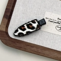 Detail of leopard print hair clip with black metal base on a textured wood tray - Black Leopard Triangle Style