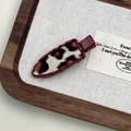 Close-up of leopard print hair clip with burgundy wavy border on rustic background - Red Leopard Triangle Style