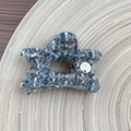 Detail of tweed star hair claw with golden metal pendant on light wood tray - Gray Star Hair Claw