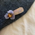 Dettaglio del fermaglio a fiore opaco viola con gemma ambrata e trama in marmo - Base in Acetato