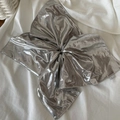 Macro shot of silver metallic bow scrunchie with shiny coating on white fabric - Silver
