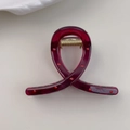 Dettaglio macro della molletta per capelli rosso scuro con pois e molla in metallo oro - Stile anello incrociato