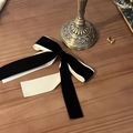 Detail van een elegante haarklem van zwart fluweel en witte stof op een houten tafel - Grote Strik Stijl / Zwart