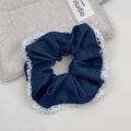 Close-up of blue denim scrunchie featuring elegant white lace edges on beige background - Lace Scrunchie