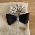 Dettaglio del fiocco in raso con perla e elastico champagne su maglia per capelli eleganti - Fiocco Nero