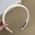 Detail view of cream sponge headband featuring a handmade fabric tag and subtle texture - Off-white