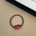 Detailed close-up of a French style red oval resin hair tie with Handmade text - Burgundy