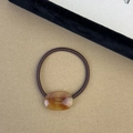 Detail view of handmade amber resin oval plate on brown woven elastic hair tie - Brown