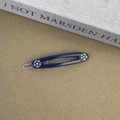 Détail d'une barrette en acétate bleu foncé ornée de strass et d'une écriture dorée - Bleu foncé