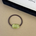 Detail of green resin oval charm with FRANCE engraving on a brown elastic hair tie - Green