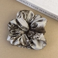 Detail of French vintage floral satin scrunchie with elegant pleated silk texture - Brown