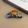 Dettaglio della molletta per capelli in acetato marmorizzato nero con sole e stelle d'oro - Sole