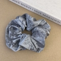 Detailed shot of grey floral satin scrunchie with vintage patterns and fabric texture - Gray