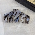 Primo piano di un grande fermaglio per capelli in acetato con trama marmo nero e bianco - Blu Nero