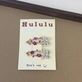 Detailed close-up of floral embroidery hair clips with white pearls on a display card - White