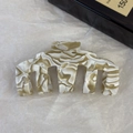 Dettaglio della grande pinza per capelli in acetato marmorizzato beige e verde oliva - Caffelatte