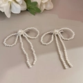 Vue macro détaillée des barrettes à perles blanches avec nœuds élégants et longs pompons - Style Blanc Perlé